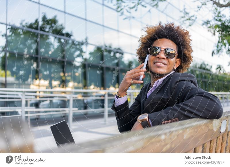 Content black businessman on a phone call on smartphone in city formal entrepreneur work male ethnic talk african american speak street suit mobile gadget style
