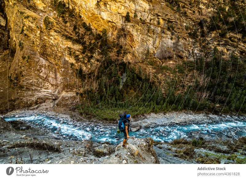 Unrecognizable traveler standing on rock near river in mountains backpacker highland adventure wanderlust viewpoint himalayas nepal stone observe admire nature