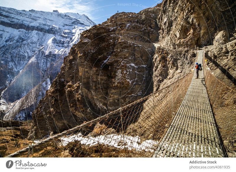 Traveler standing on suspension bridge in mountainous terrain traveler highland admire footbridge rocky adventure himalayas nepal scenic nature wanderlust