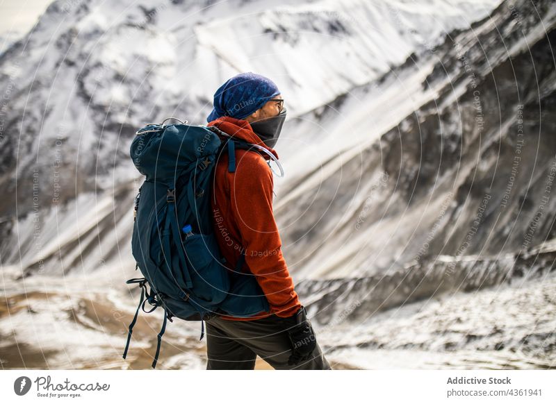Traveling man with backpack standing in snowy mountains traveler winter hiker highland adventure trekking male himalayas nepal nature hill cold outerwear ridge