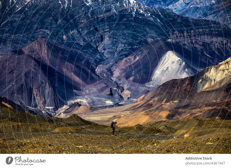 Distant view of traveler standing in mountainous valley hiker highland trekking range rocky himalayas nepal environment explore wild majestic breathtaking