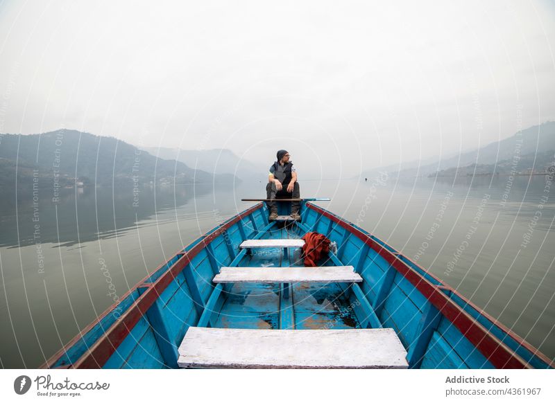 Traveling man floating in boat on lake in foggy morning traveler mist pond mountain male nepal vacation water tranquil calm haze nature highland wooden sit