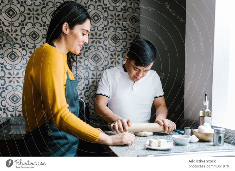 Latin mother and son with Down syndrome cooking together in kitchen down syndrome dough handicap food parent ethnic latin motherhood parenthood homemade