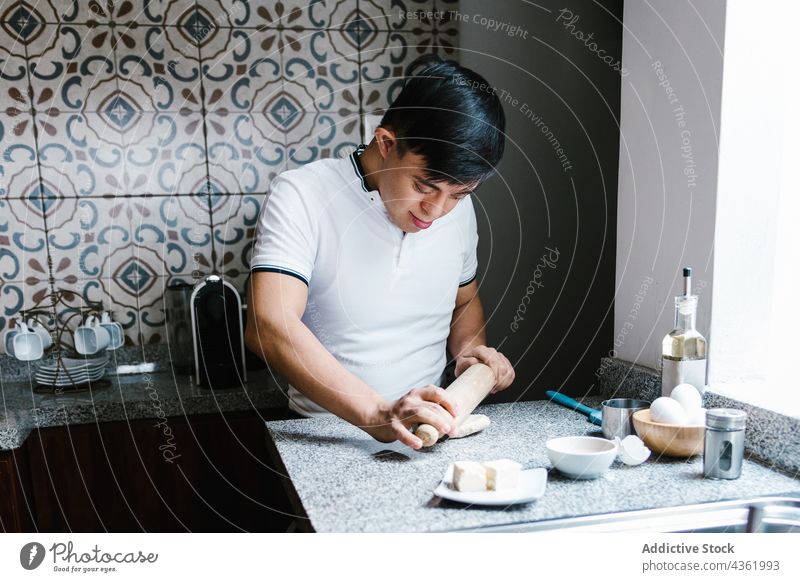 Latin boy with Down syndrome rolling dough at table down syndrome cook teenage prepare pastry kitchen ethnic latin smile happy home food rolling pin homemade