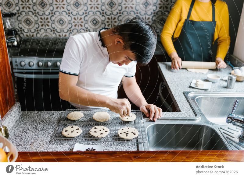 Ethnic boy with Down syndrome preparing cookies in kitchen down syndrome chocolate chip prepare bakery raw ethnic latin teen sweet table fresh food handicap