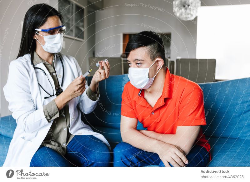 Doctor filling syringe with vaccine for ethnic boy with Down syndrome doctor coronavirus down syndrome patient covid 19 health care latin home prepare medicine
