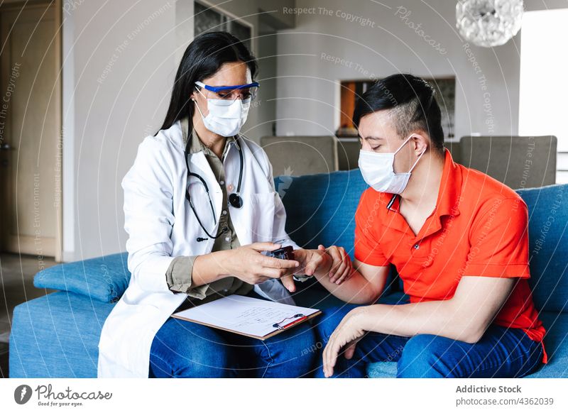 Doctor using pulse oximeter on finger of ethnic boy with Down syndrome doctor patient down syndrome check appointment home mask protect latin device health care