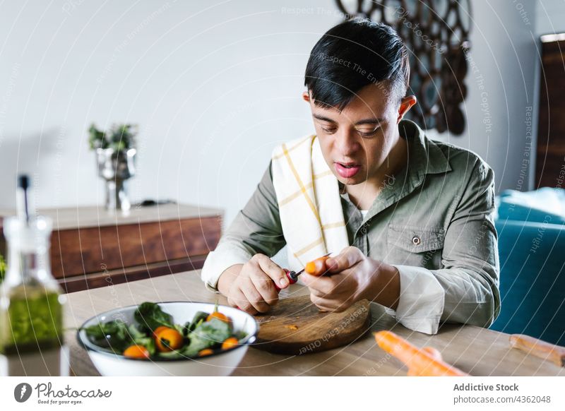 Latin boy with Down syndrome cooking salad together down syndrome help cut vegetable lunch ethnic latin disorder disable mental handicap prepare kitchen home