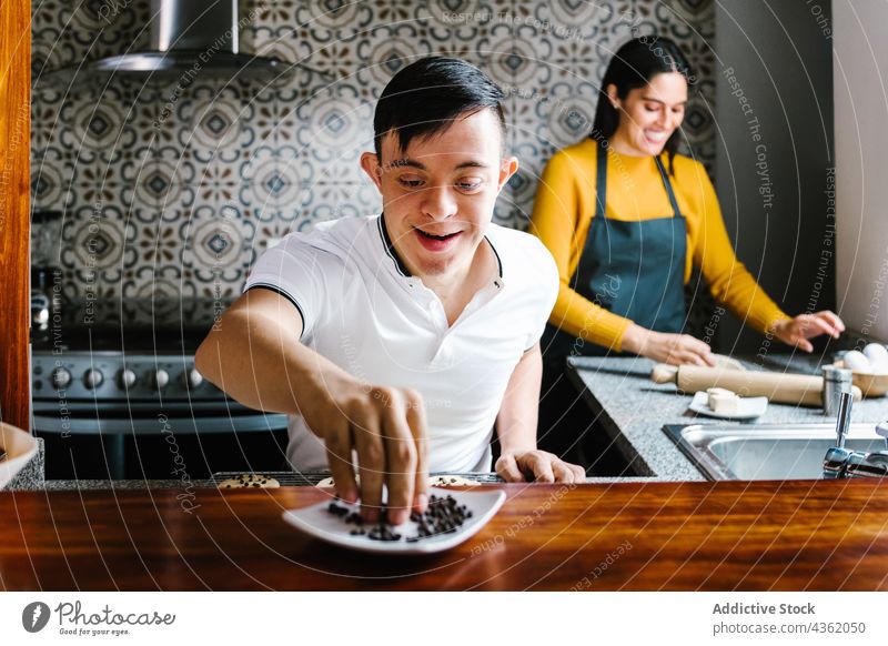 Cheerful Latin boy with Down syndrome cooking with mother in kitchen down syndrome together cookie prepare bakery cheerful latin ethnic son teen teenage