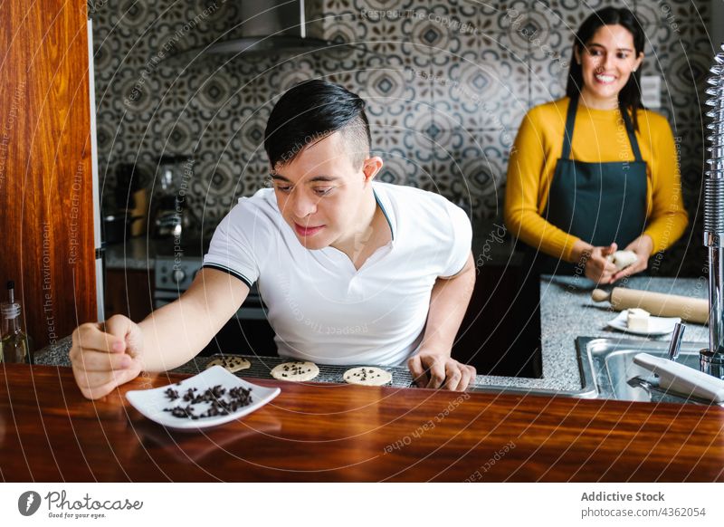 Cheerful Latin boy with Down syndrome cooking with mother in kitchen down syndrome together cookie prepare bakery cheerful latin ethnic son teen teenage
