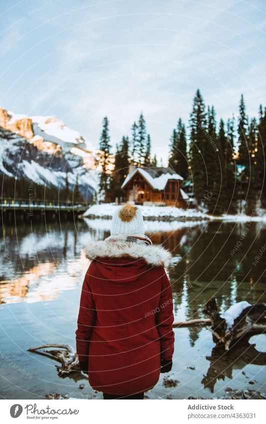 Anonymous woman standing on snowy lake shore near mountain and hut tourist winter admire travel emerald lake british columbia canada banff national park