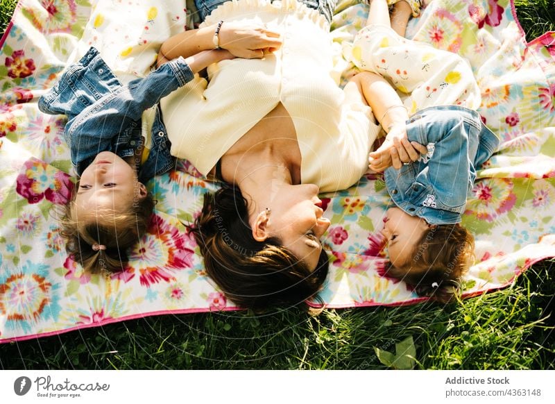 Little siblings with mom resting on blanket in park mother kid together happy summer love daughter similar cute child relationship little children sister alike
