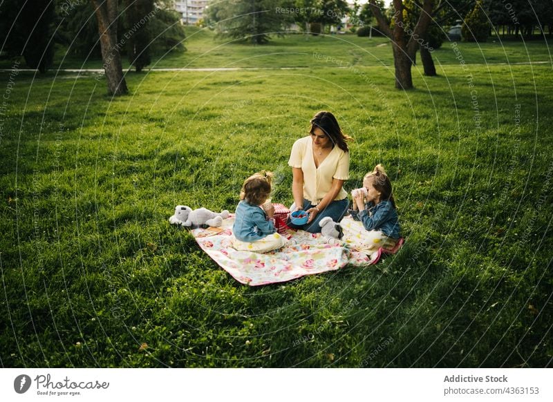 Cheerful mother and kids having picnic in park together summer happy love daughter sibling drink cup child mom relationship little children sister bonding