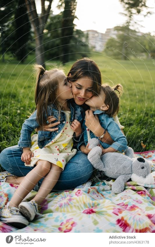 Loving mother with kids in green park kiss love together happy daughter summer sibling cute cuddle child mom relationship little children sister bonding