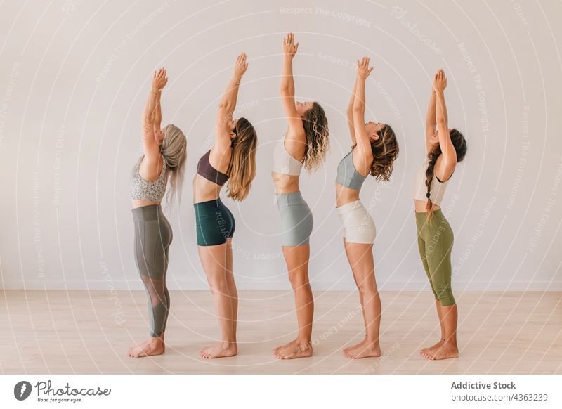 Company of women doing yoga in Mountain pose with raised arms group class practice mountain pose namaste arms raised studio lesson female together wellness zen