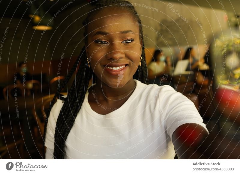 Black woman taking selfie in cafe cheerful smile self portrait braid chill entertain having fun female ethnic black african american using charming take photo