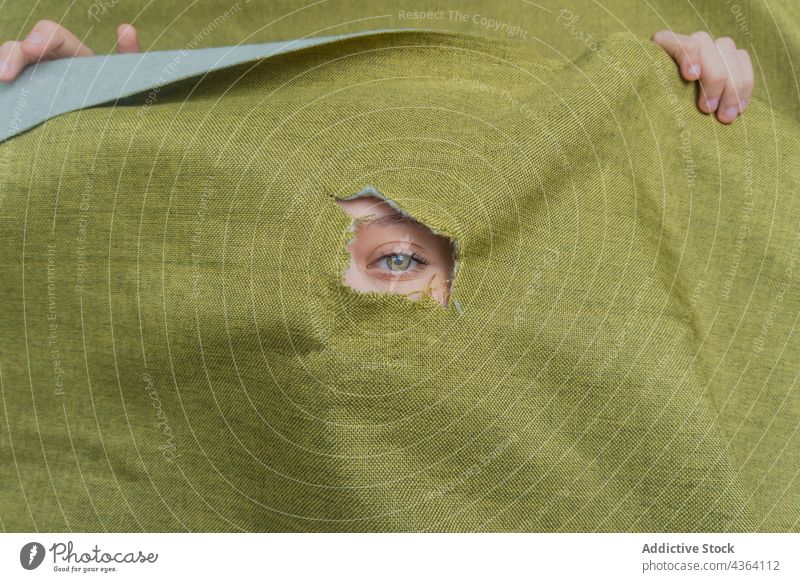Woman with green eyes looking through hole in fabric woman color gaze stare hide cloth mystery beauty cover face female young feminine peep behind eyelashes