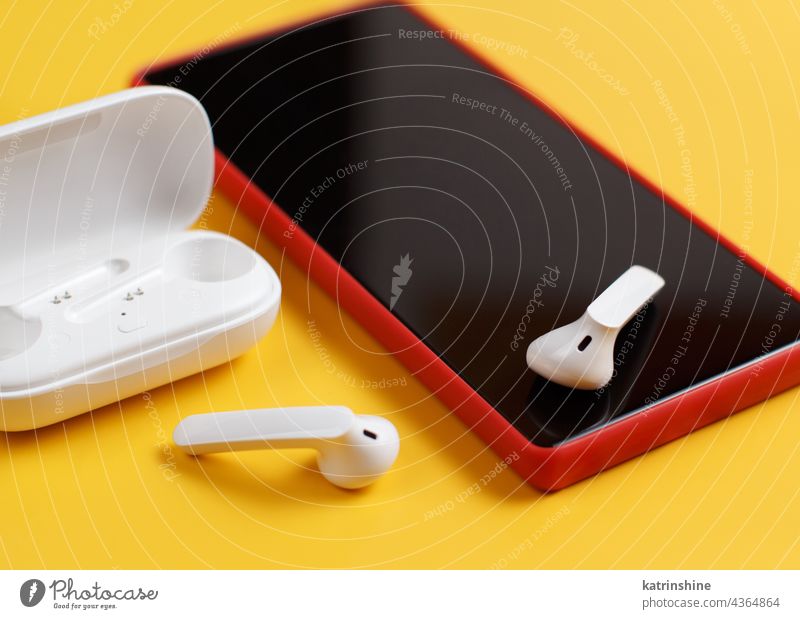Smartphone and wireless earphones with opened case on yellow background smartphone mockup white red close up Headphones Accessories Mobile cell phone