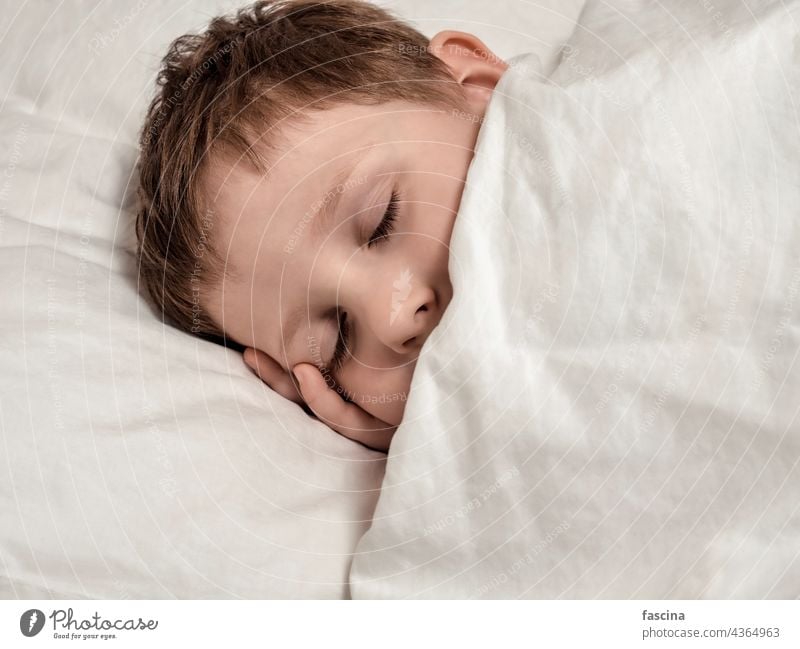 Sleeping young boy in white bed sleeping boy sleeping child little face closeup childhood relaxation person pillow copy space one portrait toddler cute small