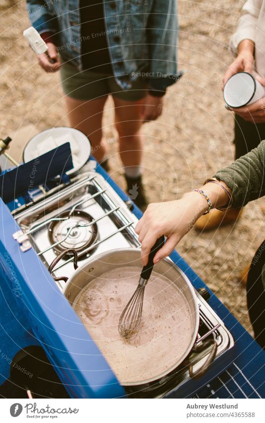 woman stirring hot chocolate on a camp stove outdoors blue camping chef community cook cooking cookware culinary flat lay food group heat kitchen knife meal