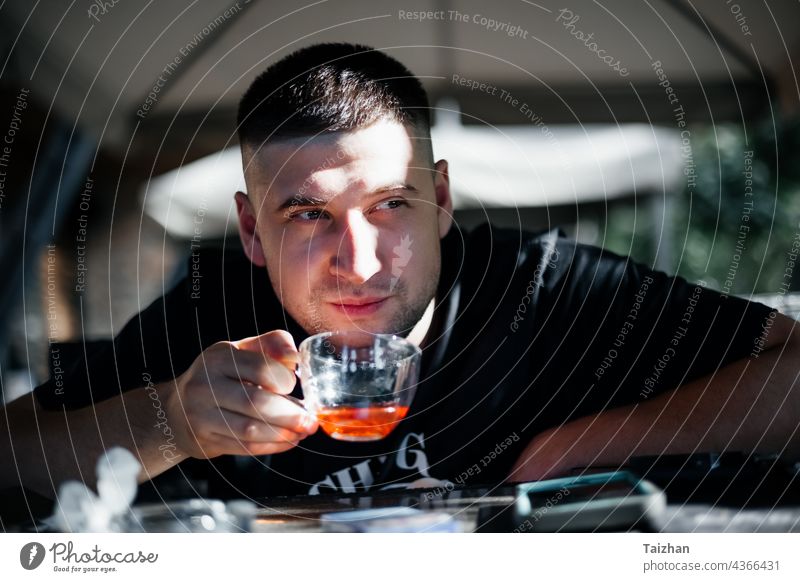 Close up of man drinking tea at   cafe person looking male sitting caucasian cheerful mug cup alone close up enjoyment fashionable fingers guy handsome heat