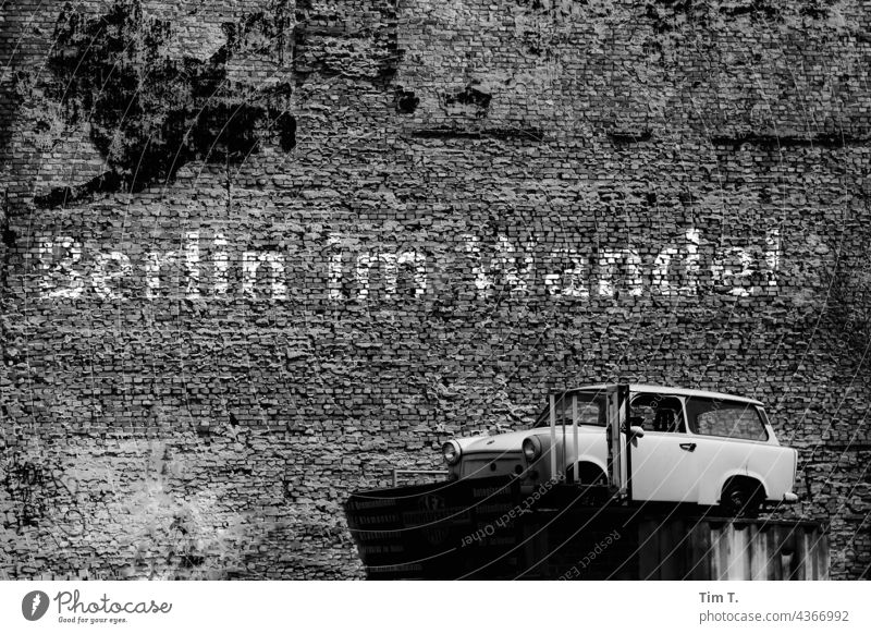 an old yard with a Trabant car and a graffiti " Berlin in the change ". b/w trobant Town Deserted Graffiti Exterior shot Downtown Capital city