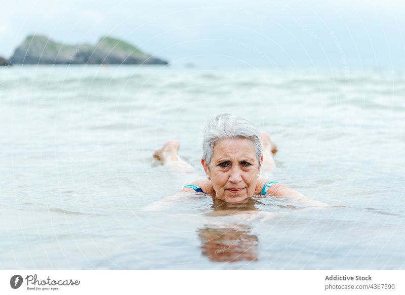 Old woman swimming in sea water senior beach active summer ocean healthy lifestyle female old aged gray hair enjoy bath practice nature summertime recreation