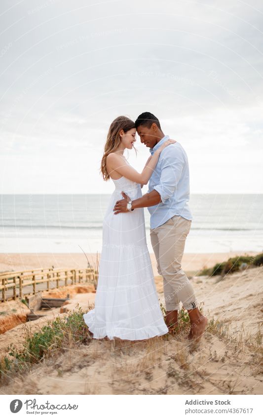 Gentle multiethnic newlyweds embracing on hill on seashore couple beach embrace love wedding bride groom multiracial diverse black african american relationship