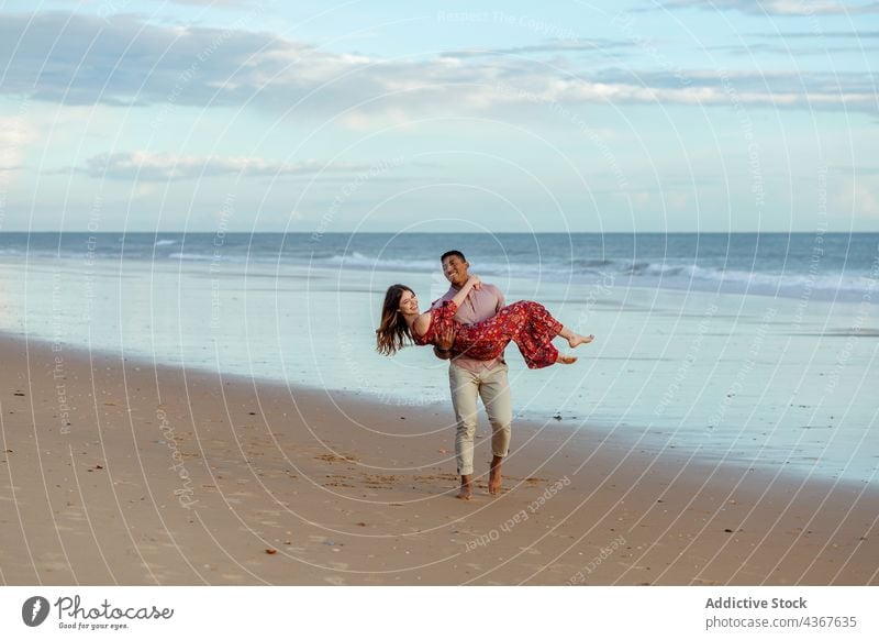 Delighted multiracial couple having fun on beach carry together love sea enjoy seashore sunset multiethnic diverse black african american summer coast nature