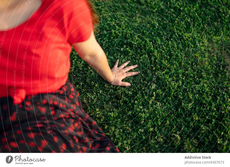 unrecognizable crop woman chilling on lawn in park summer serene harmony sunset peaceful meadow enjoy female grass nature field sit calm tranquil carefree
