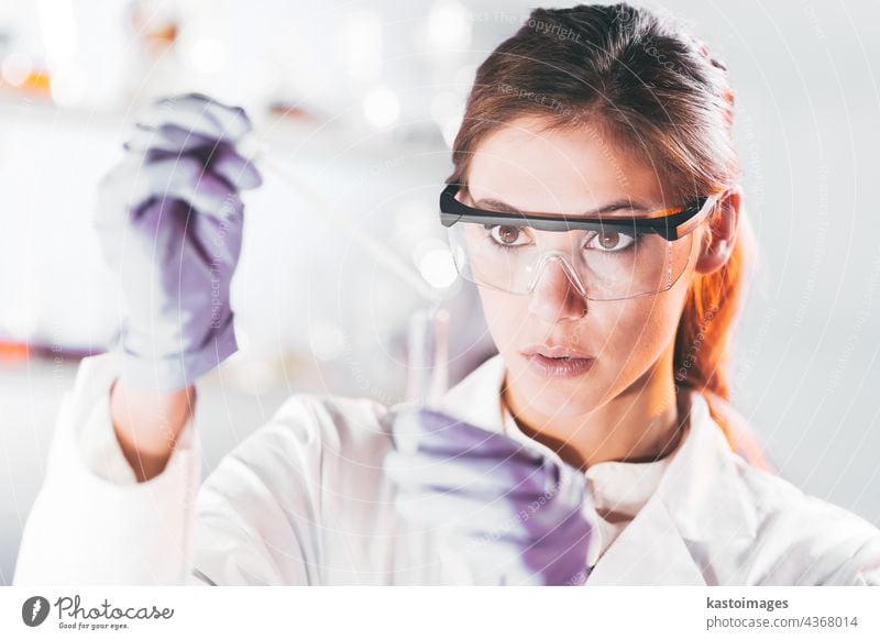 Young scientist pipetting in life science laboratory. research woman technology analysis experiment analyzing biotechnology healthcare researcher blue chemical