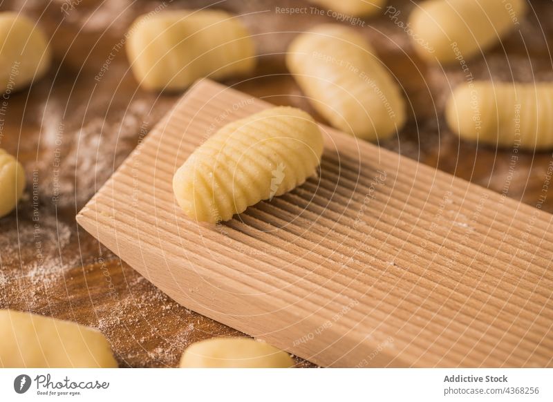Raw pieces of dough near ribbed board gnocchi raw cook table flour ingredient kitchen prepare food fresh pasta italian authentic tradition meal homemade soft