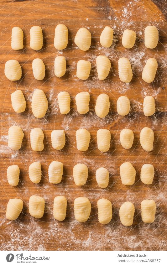 Raw gnocchi on wooden table raw pasta cook row kitchen home lunch food meal prepare dish cuisine portion culinary italian tradition authentic fresh lumber