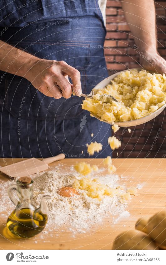 Crop cook adding potato to flour and egg man mashed dough kitchen home male gnocchi pasta recipe prepare cuisine fresh homemade food ingredient raw apron