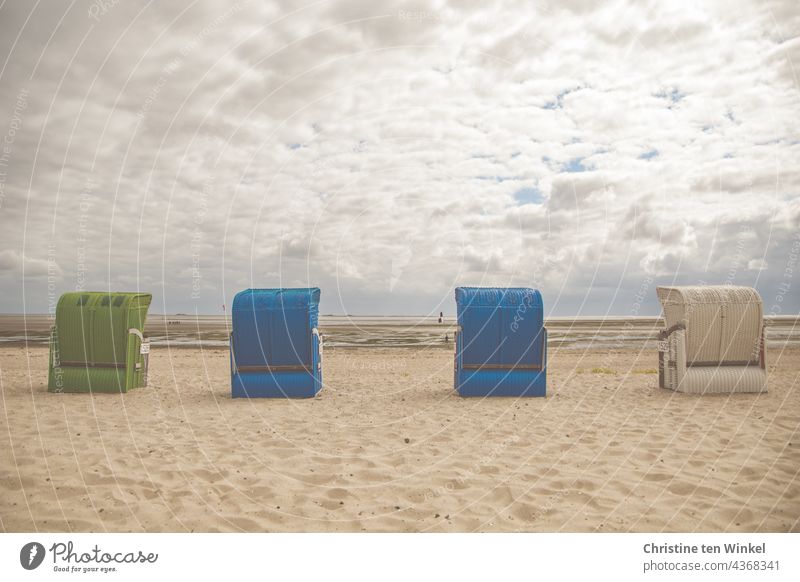Four beach chairs stand on the empty beach in cloudy weather and low tide and wait for guests Beach chair tranquillity North Sea beach Deserted Summer Sand