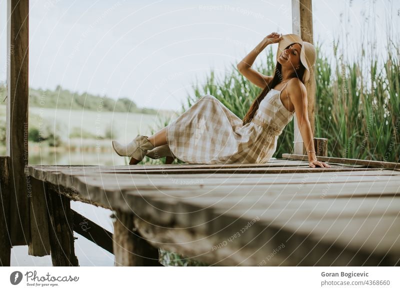 Relaxing young woman on wooden pier at the lake beautiful concept enjoy summer nature caucasian good casual female sunny dream person vacation leisure rest
