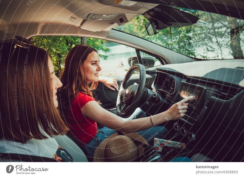 Two young girls listening to good music while driving in car, enjoy summer road trip in nature. together travel female vacation friends adventure happy outdoors