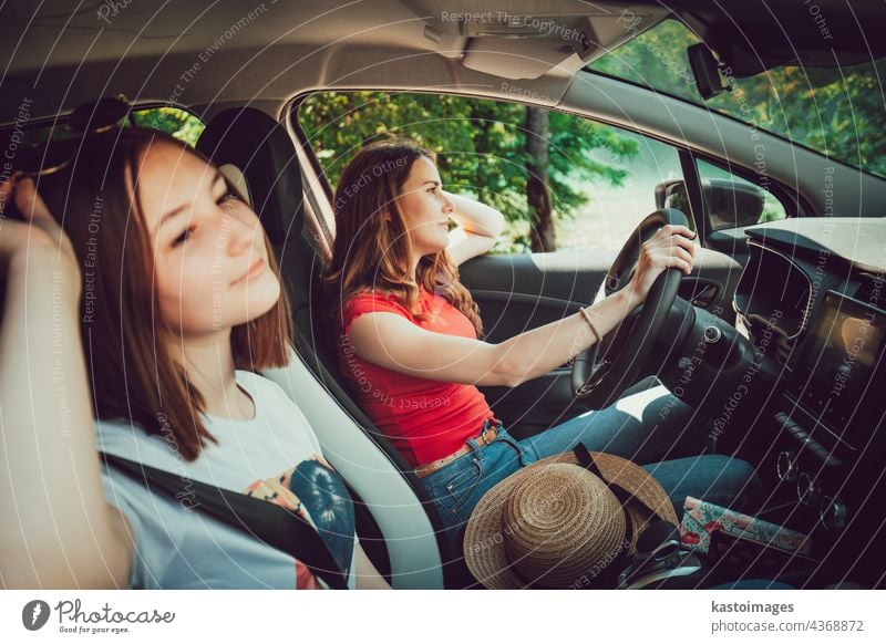 Two young girls driving in car, enjoy summer road trip in nature. together travel female vacation friends adventure happy outdoors women smiling caucasian