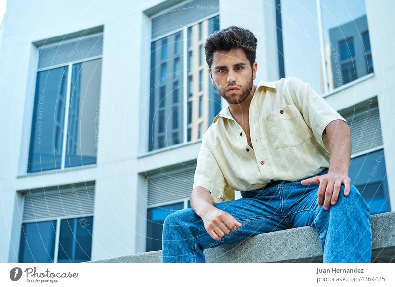 man posing in front of a building with large windows young men university college campus education guy school student study studying outside handsome horizontal