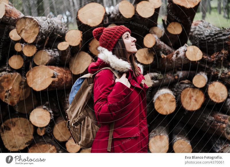 backpacker woman in front of wooden trunks in mountain. Autumn or winter season. Nature and lifestyle hiking caucasian forest autumn cold coat hat camping hike
