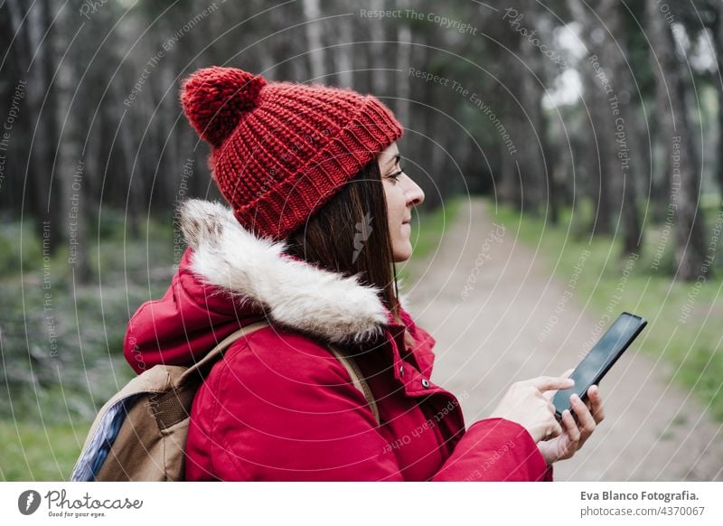 close up of backpacker caucasian woman walking in forest using mobile phone during winter or autumn season. Lifestyle and nature. Wide angle view technology