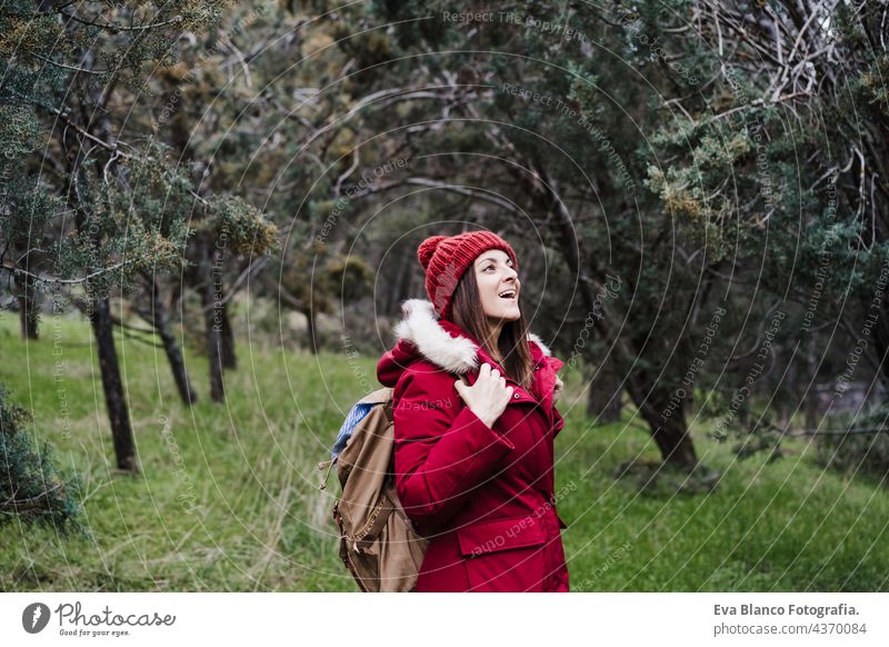 happy backpacker caucasian woman walking in forest during winter or autumn season. Lifestyle and nature hiking mountain cold coat hat camping hike active