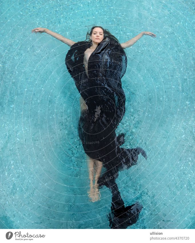 beautiful young woman in black dress, elegant swimming in pool dark brown curly hairs fan shape in water holiday bathing summer sea blue fun happy sport