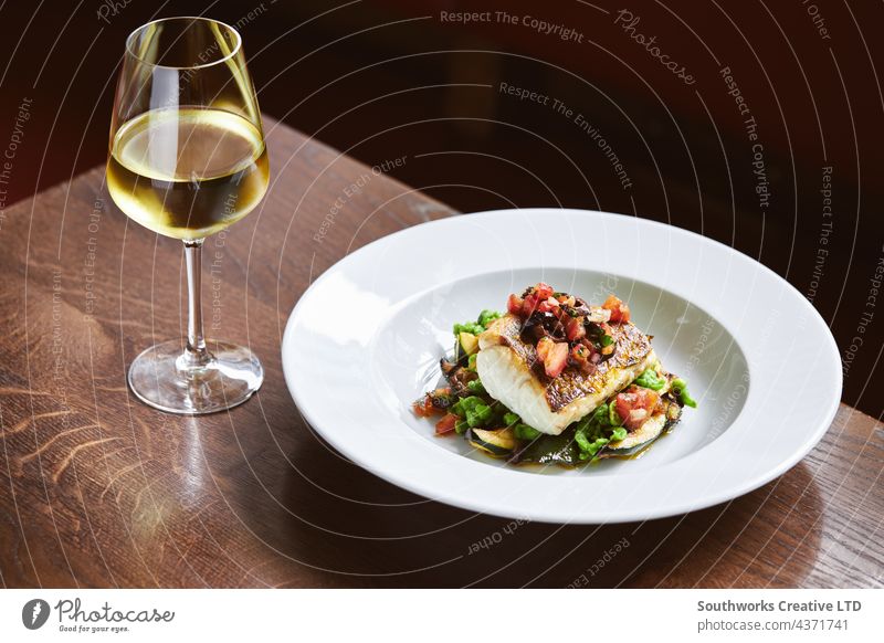 White wine and cod dish in restaurant white wine fish meal hospitality food drink still life indoors day dine eat table modern contemporary luxury gourmet