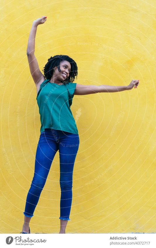 Laughing young African woman in front of yellow wall with raised laughing african people happy portrait american model lady ethnicity afro smiling girl