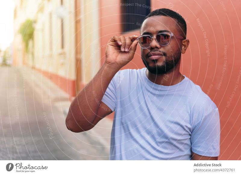 African man with sunglasses walking in the city street looking at the camera. confident male adult african american black ethnicity photography people men