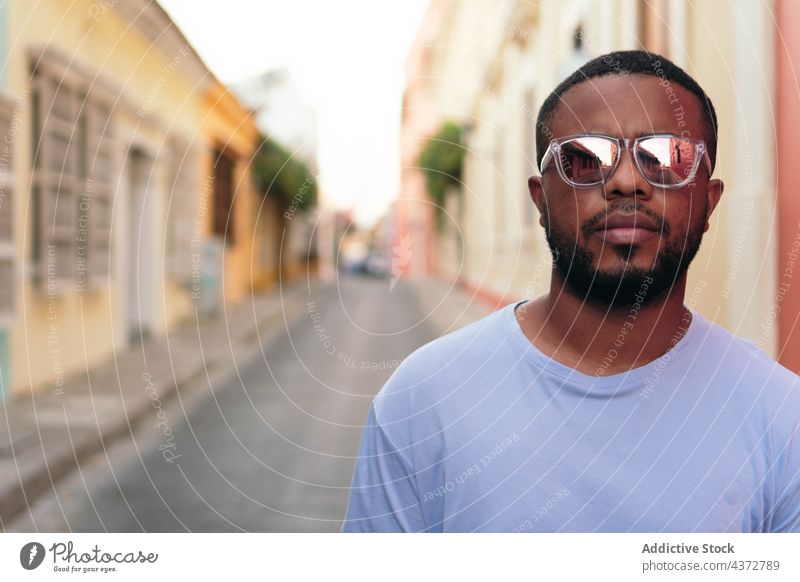 Portrait of stylish African American man walking with sunglasses outdoors. Fashionable black man in the street. confident male adult african american ethnicity