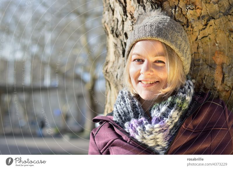 Young blonde woman leaning against tree | close to nature Looking into the camera Front view Day Joie de vivre (Vitality) Positive naturally pretty Happiness