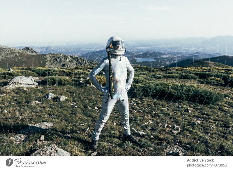Confident spaceman standing in countryside confident mission brave concept highland explore science spacesuit male astronaut helmet adventure protect cosmonaut