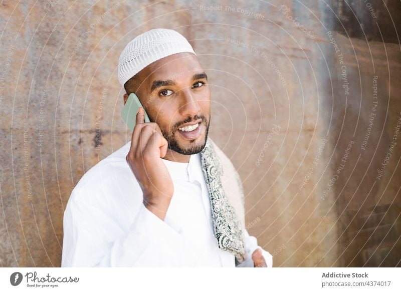 Islamic man using smartphone on street muslim arab islam smile tradition wall shabby social media rest male cellphone gadget device browsing ethnic religion
